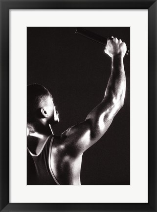 Framed Male runner holding up a relay baton Print