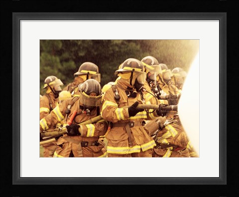 Framed Group of firefighters spraying water with a fire hose Print