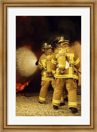 Framed Rear view of three firefighters extinguishing a fire Print