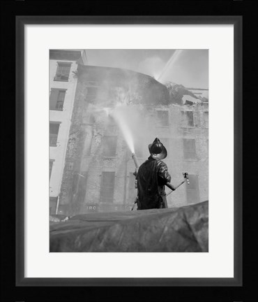 Framed Firefighter pouring water on burning building, low angle view Print