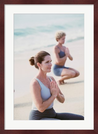 Framed Young woman and a mid adult woman meditating on the beach Print