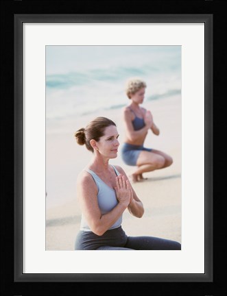 Framed Young woman and a mid adult woman meditating on the beach Print