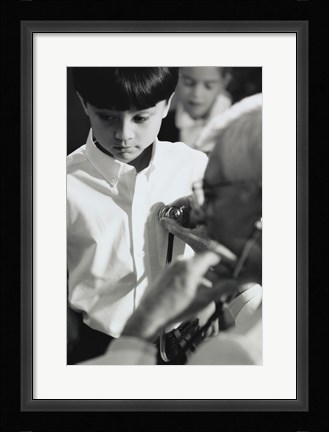 Framed Male doctor listening to a boy's heartbeat Print