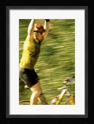 Framed Young man sitting on a bicycle with his arms raised Print