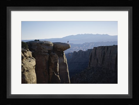 Framed Side profile of a young man pulling a young woman onto a rock Print