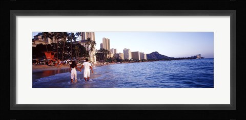 Framed Rear view of a couple wading on the beach, Waikiki Beach, Honolulu, Oahu, Hawaii, USA Print