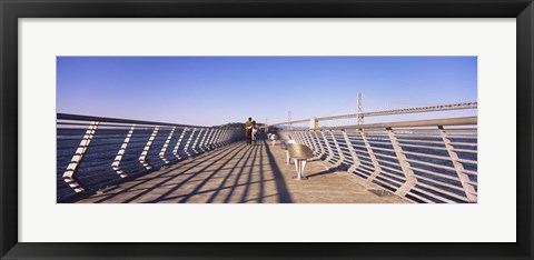 Framed Couple walking on a pier, Bay Bridge, San Francisco, California, USA Print