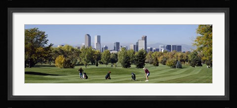 Framed Four people playing golf with buildings in the background, Denver, Colorado, USA Print