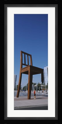 Framed Woman standing under a sculpture of large broken chair, Geneva, Switzerland Print