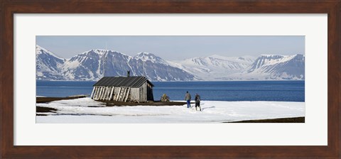Framed Two hikers standing on the beach near a hunting cabin, Bellsund, Spitsbergen, Svalbard Islands, Norway Print