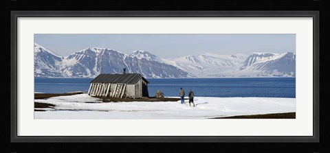 Framed Two hikers standing on the beach near a hunting cabin, Bellsund, Spitsbergen, Svalbard Islands, Norway Print
