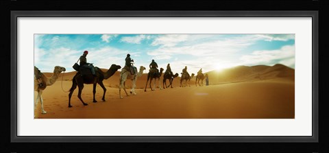 Framed Tourists riding camels through the Sahara Desert landscape led by a Berber man, Morocco Print