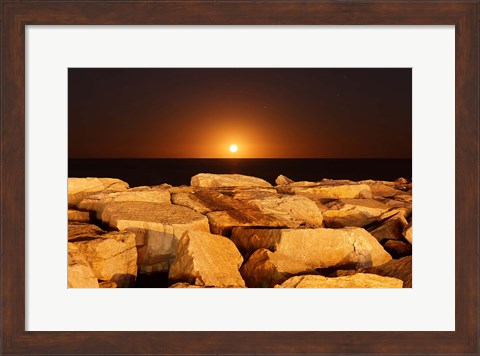 Framed moon rising behind rocks lit by a nearby fire in Miramar, Argentina Print